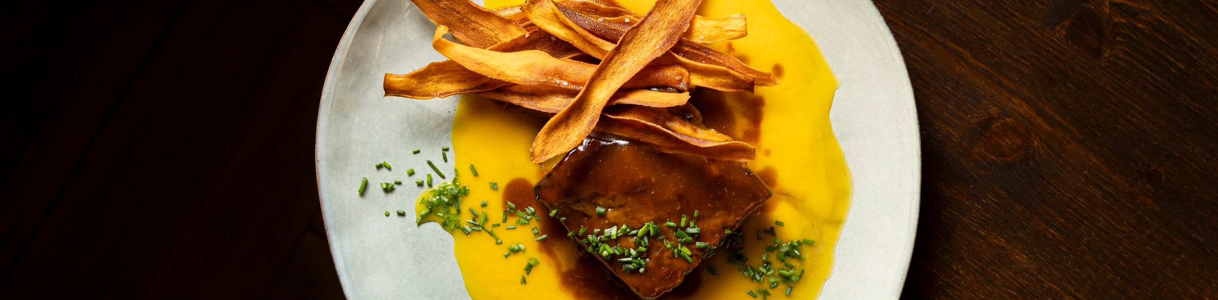 Fotografía gastronómica de Rubén Bresó: plato con salsa amarilla y láminas crujientes.